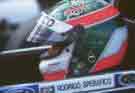 side on close up of Rodrigo Specrifico in his 
helmet sitting in his race car.